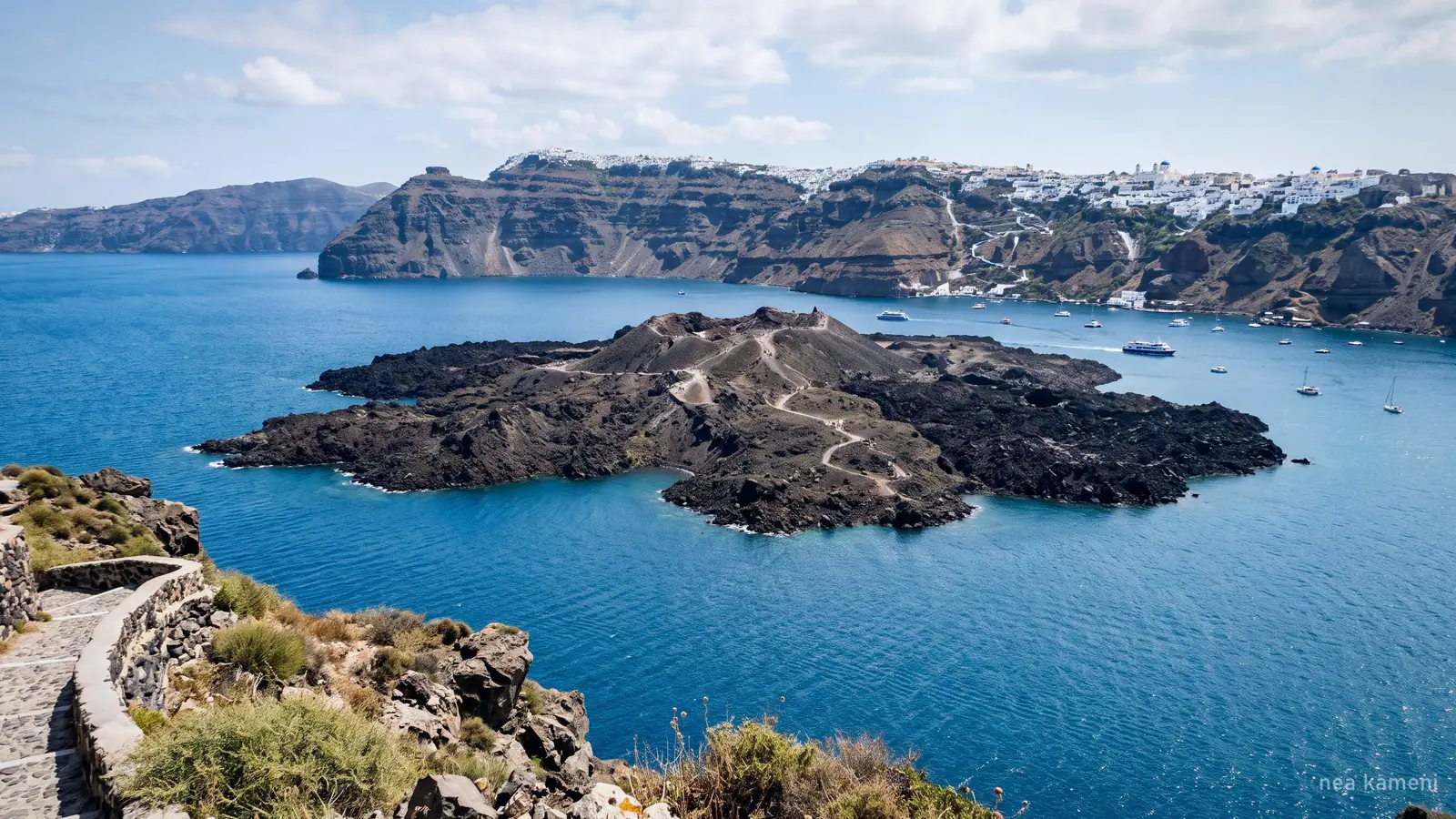 Nea Kameni, ciemna wulkaniczna wyspa w środku kaldery Santorini, widziana z krawędzi klifu