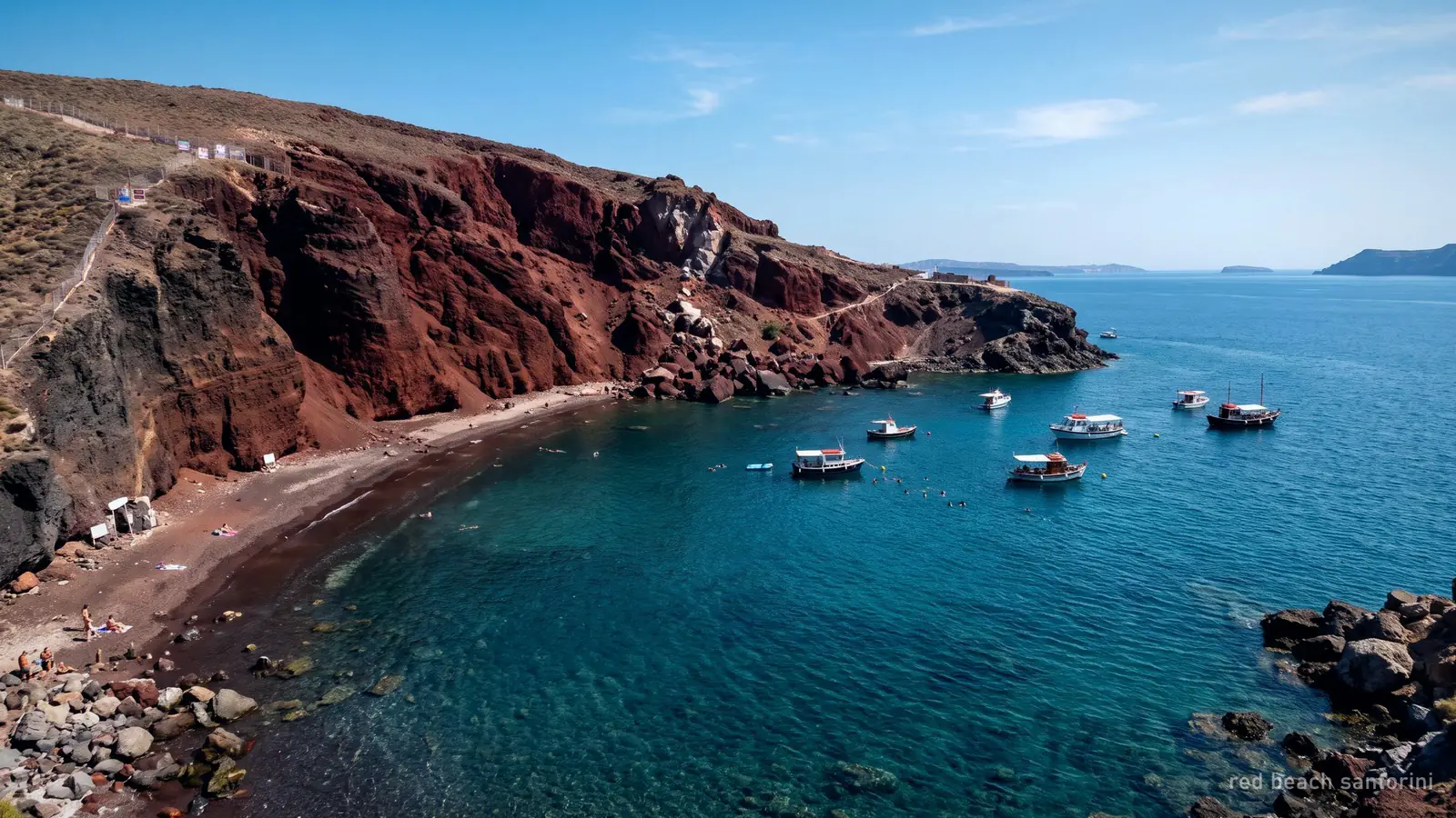 La Spiaggia Rossa vicino ad Akrotiri sotto la sua scogliera vulcanica rossa, con barche ancorate al largo