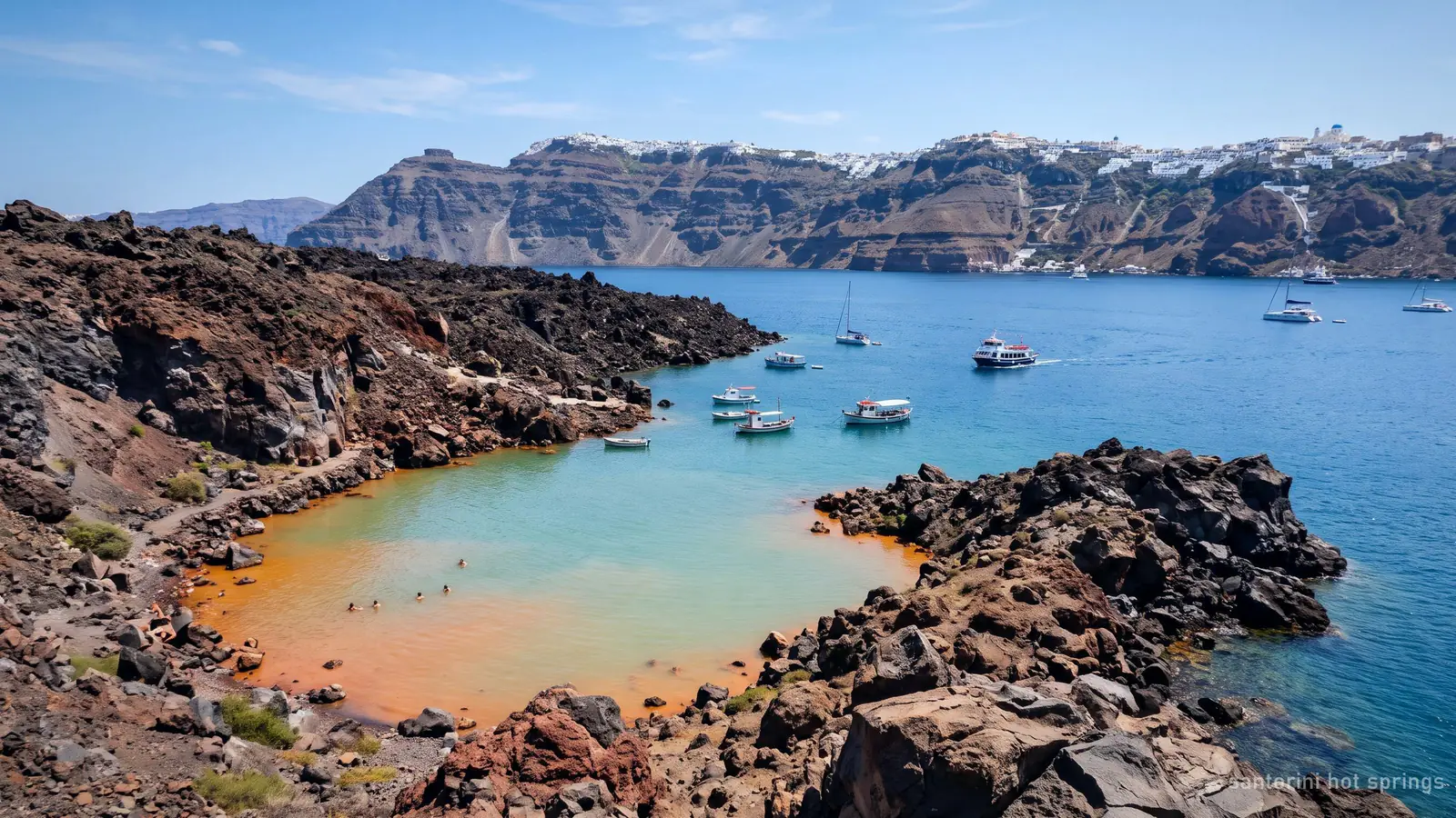 The orange-tinted warm water of the hot springs cove at Palea Kameni, boats anchored outside