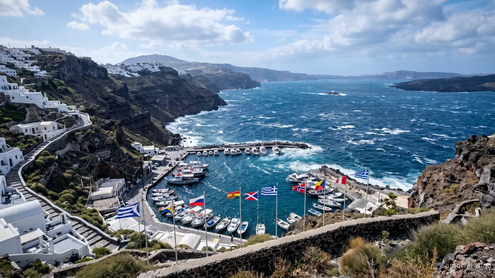 Whitecaps across the Santorini caldera and boats sheltering in a harbour on a windy day