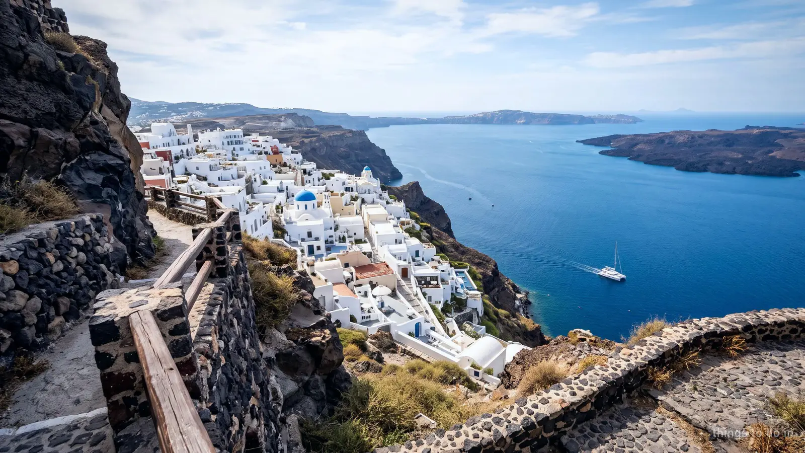 White houses on the caldera rim at Imerovigli above the sea, a boat far below